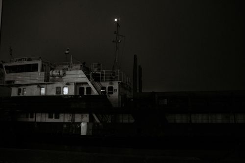 Free A dark and atmospheric black and white photo of a ship illuminated at night. Stock Photo