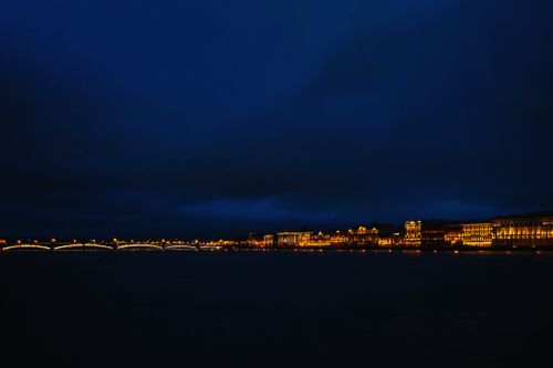 Free Captivating night skyline with illuminated buildings and serene water reflection. Stock Photo