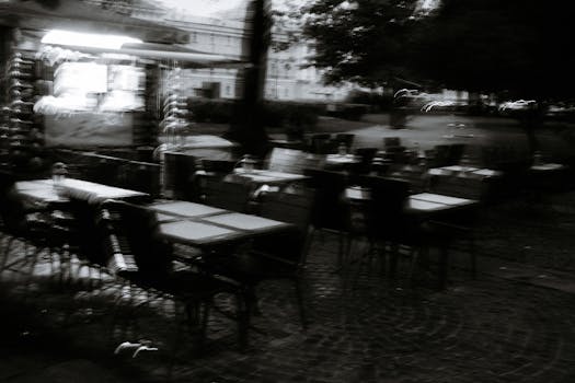 Blurred chairs and tables outside in a dreamy, monochrome setting.