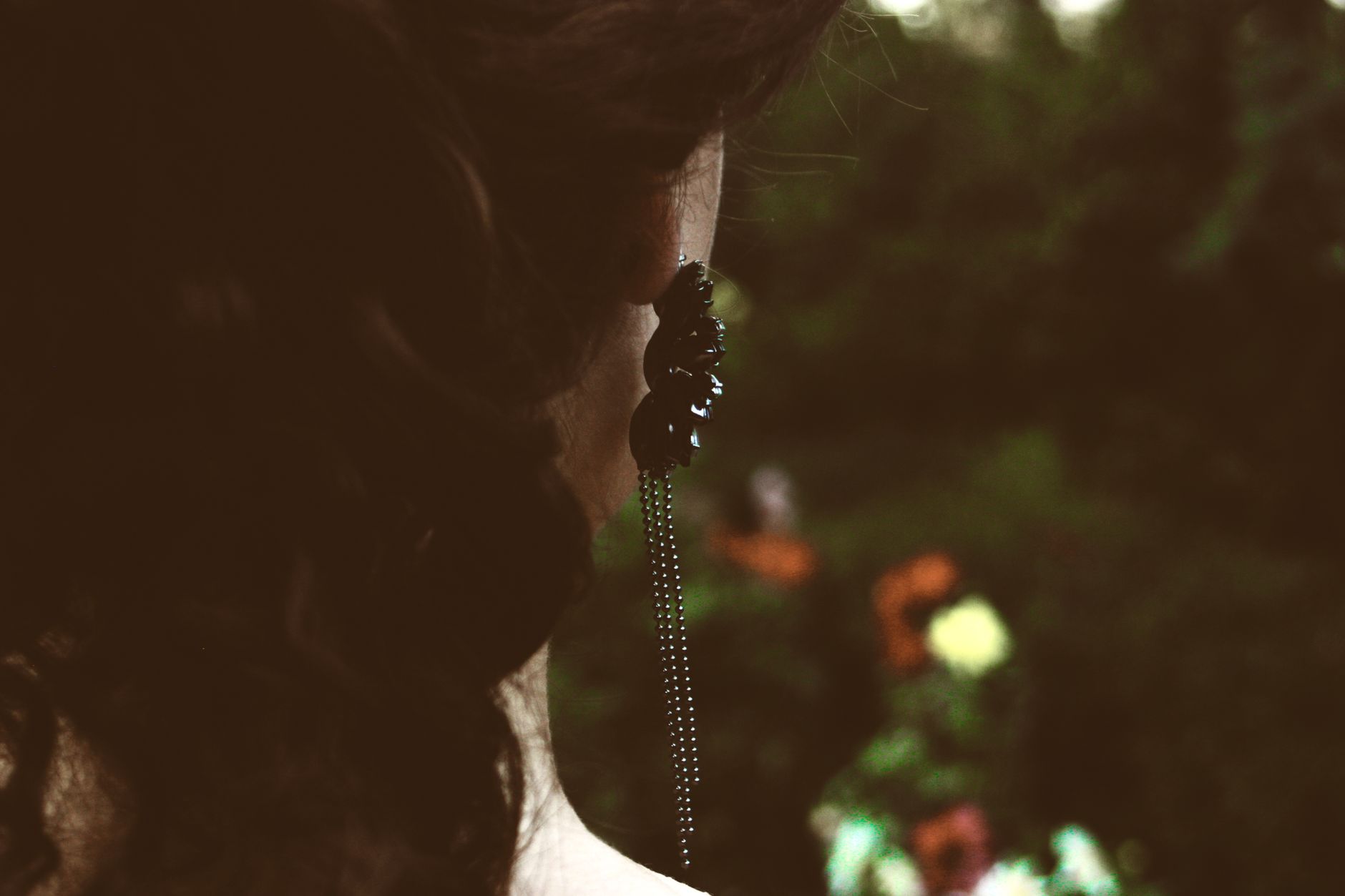 Close-up portrait of a woman wearing an elegant earring amid a natural, blurred background.