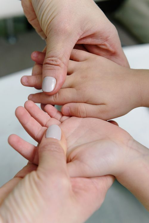 Free Adult giving a soothing hand massage to a child's hand, emphasizing care and relaxation. Stock Photo