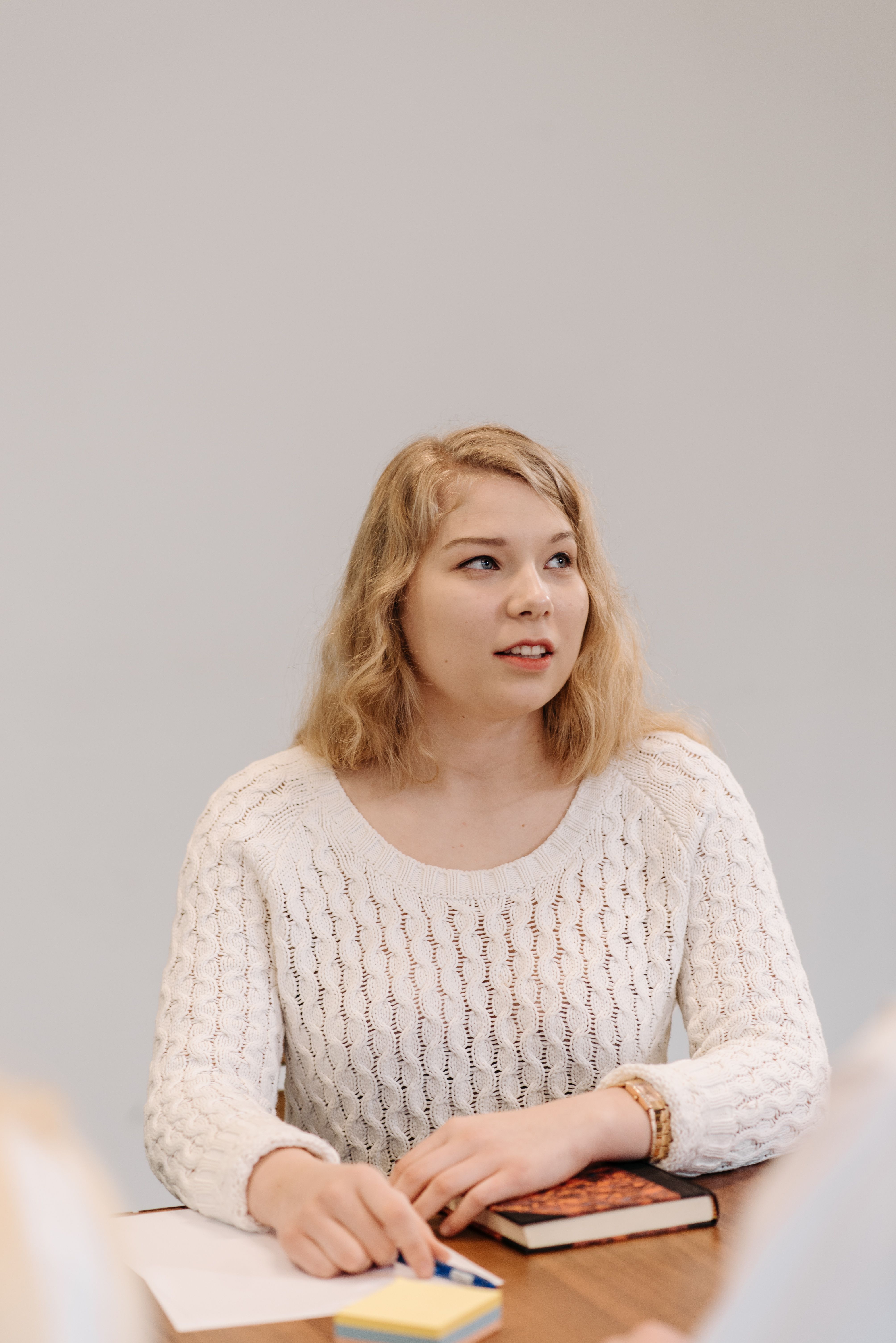 Woman in a White Sweater Sitting at a Table · Free Stock Photo
