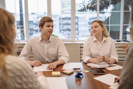 A group of young adults collaborating around a table in a modern office setting.