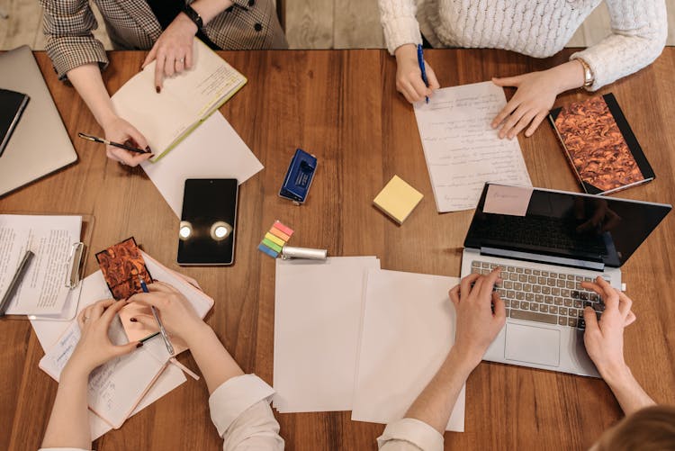 Top View Shot Of People Busy Doing Their Tasks On The Table