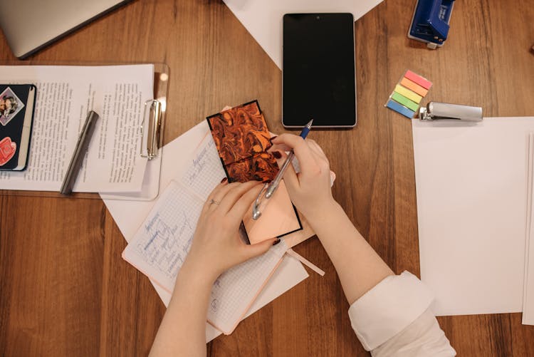 Hands Of A Woman Holding A Pen And A Notepad