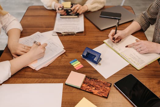 Three colleagues engaged in a collaborative meeting taking notes and reviewing documents.