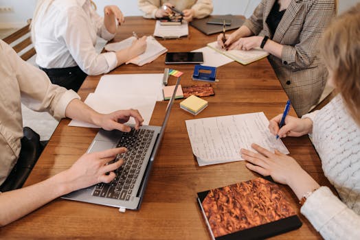 A group of professionals collaborating during a meeting with laptops and notepads.