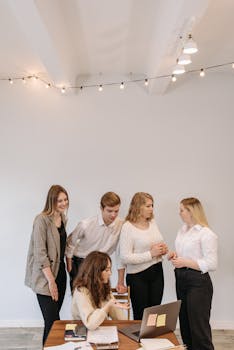Five colleagues gather around a laptop for a brainstorming session.