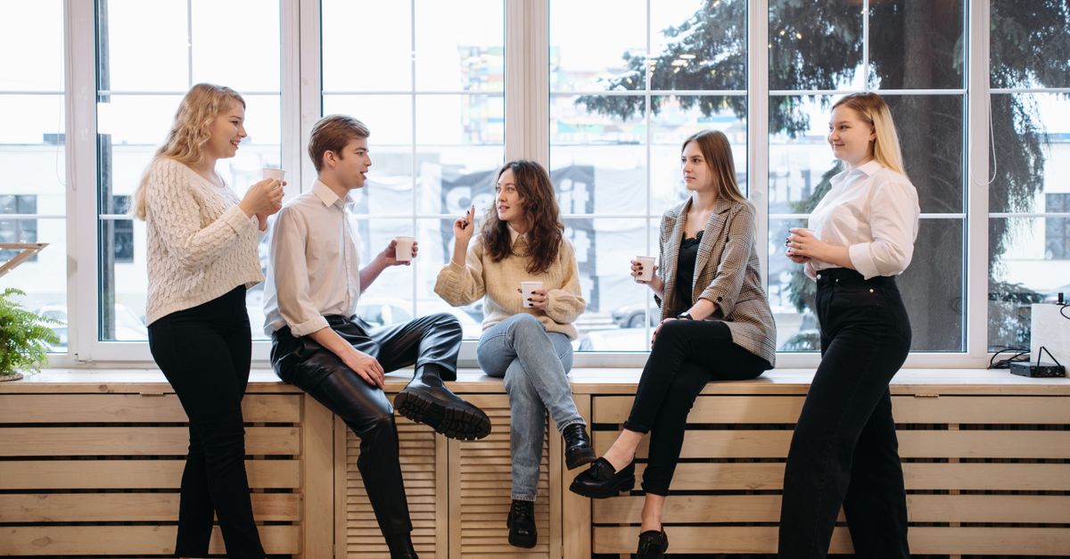 A group of people talking easily over coffee by a window.