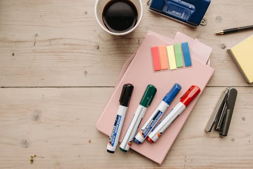 A Cup of Coffee and Stationeries on a Wooden Surface