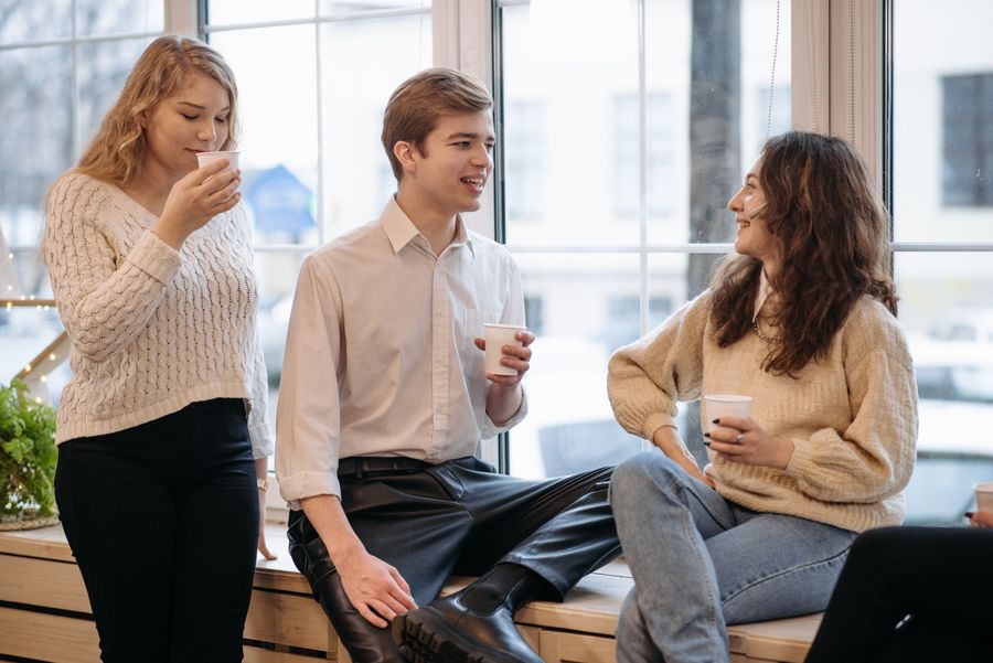 Young people talking over coffee by a window