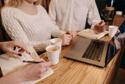 Free Informal team meeting over coffee with laptops and notes, fostering collaboration. Stock Photo
