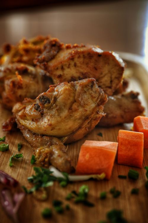 Free Close-up of grilled chicken wings with fresh vegetables on a wooden board. Stock Photo