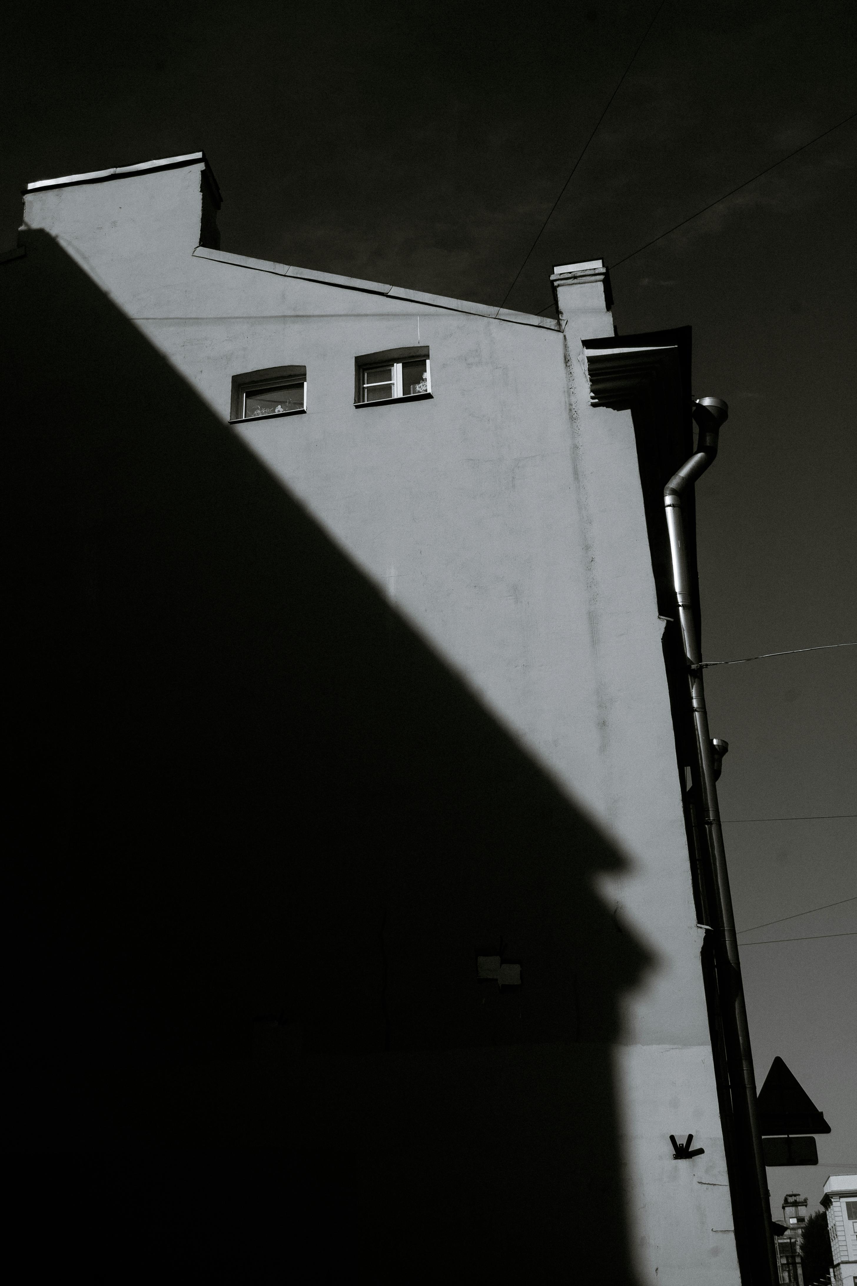 Photograph of a building showing dramatic shadows on its facade, in monochrome.