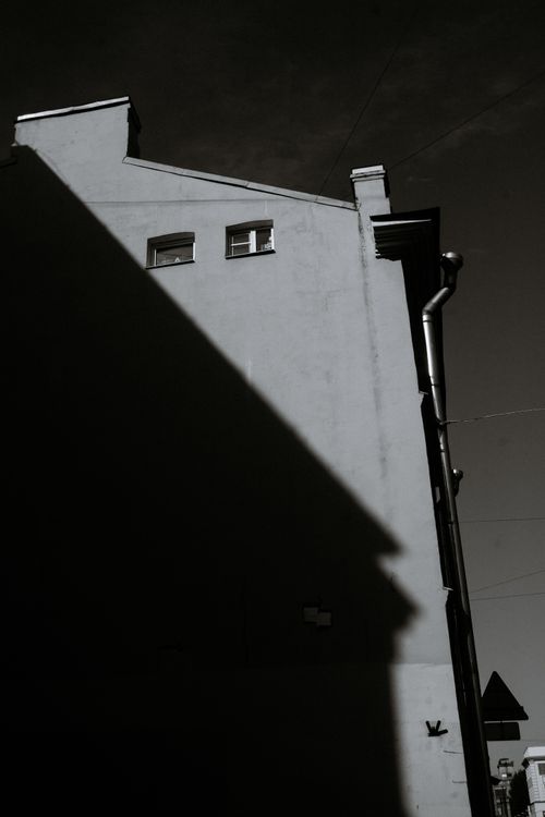 Free Photograph of a building showing dramatic shadows on its facade, in monochrome. Stock Photo
