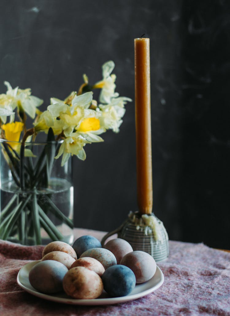 Easter Eggs And Candle On Table Near Flowers In Vase