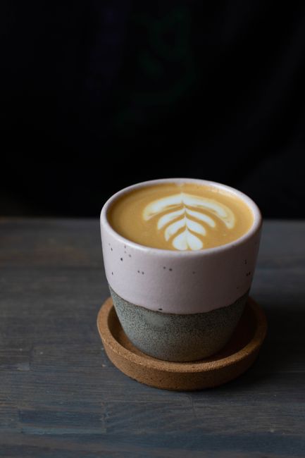 Ceramic cup of aromatic freshly brewed cappuccino with fluffy froth served on black wooden table
