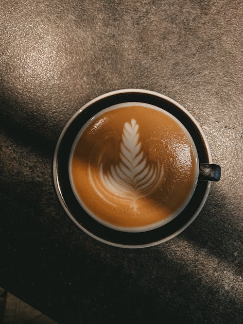 Top view fragrant freshly brewed cappuccino with foam served on table in modern cafe