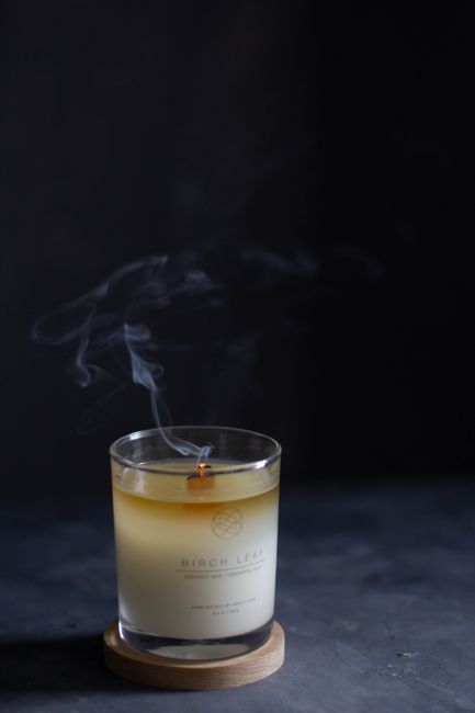 Glass jar with aromatic extincting candle placed on black table in dark room