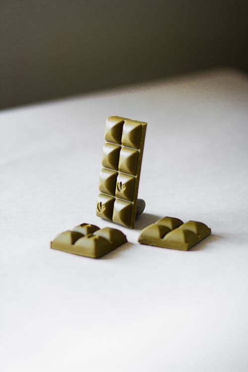 Composition of green tea chocolate bar pieces arranged on white table in studio