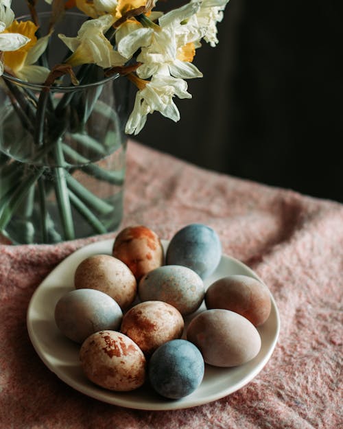 Free From above composition of painted eggs placed on table near vase with delicate flowers during Easter holiday Stock Photo