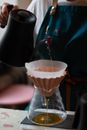 Crop faceless barista pouring hot water into chemex