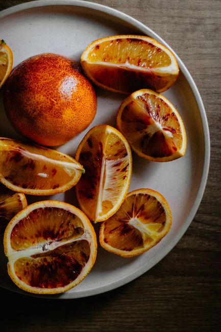 Top view of tasty fresh juicy citrus fruit pieces placed on ceramic plate on wooden table