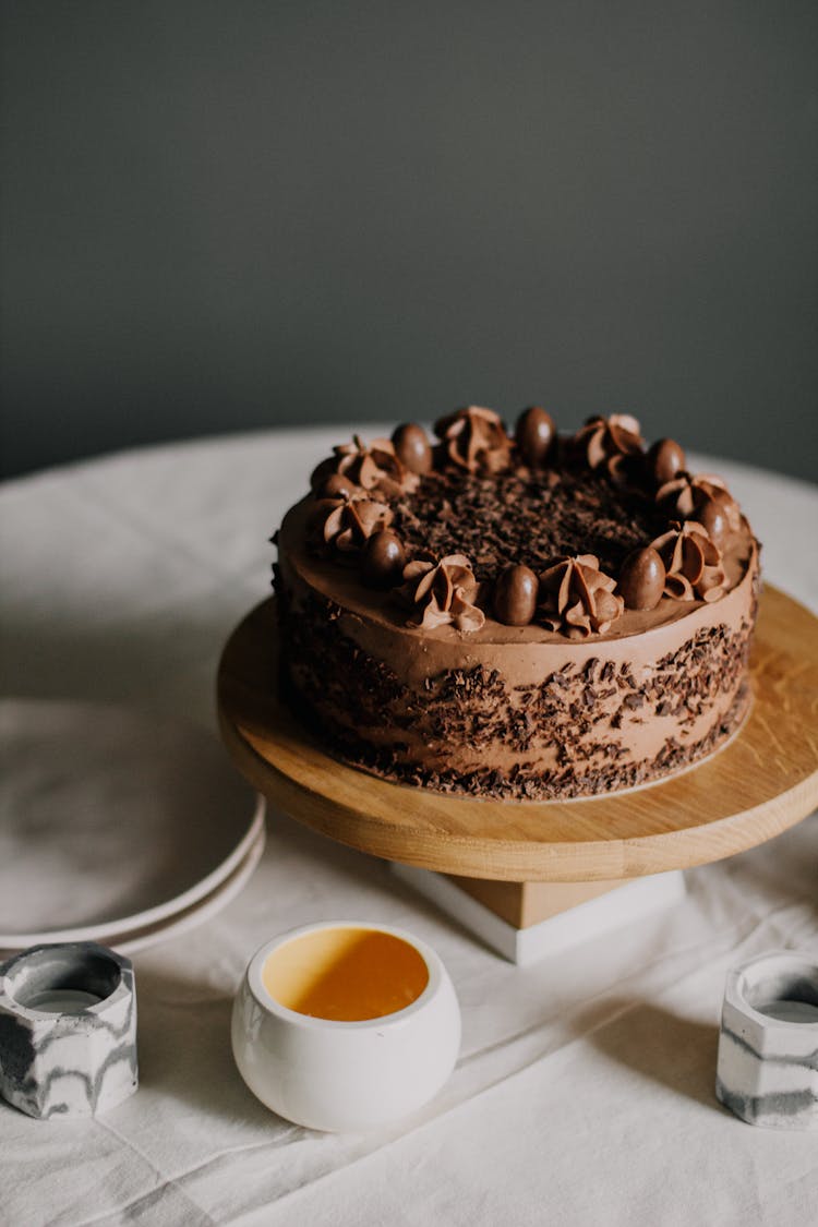 Chocolate Cake On Wooden Stand Near Ceramic Dishes