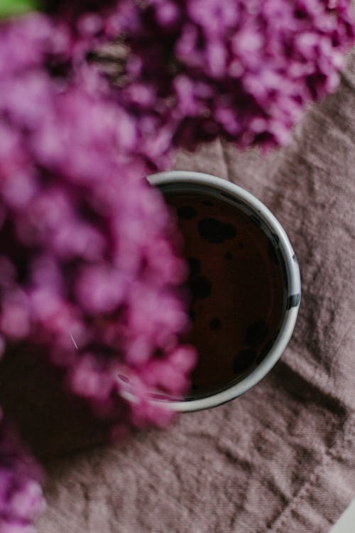 Free Top view of lush lilac bunch above mug of tea on wrinkled cloth Stock Photo