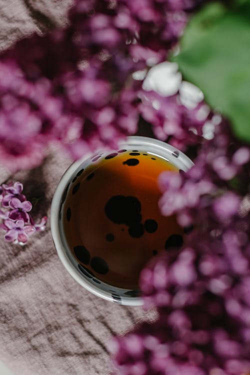 Top view of cup of tea placed near fresh branches of lilac with purple petals