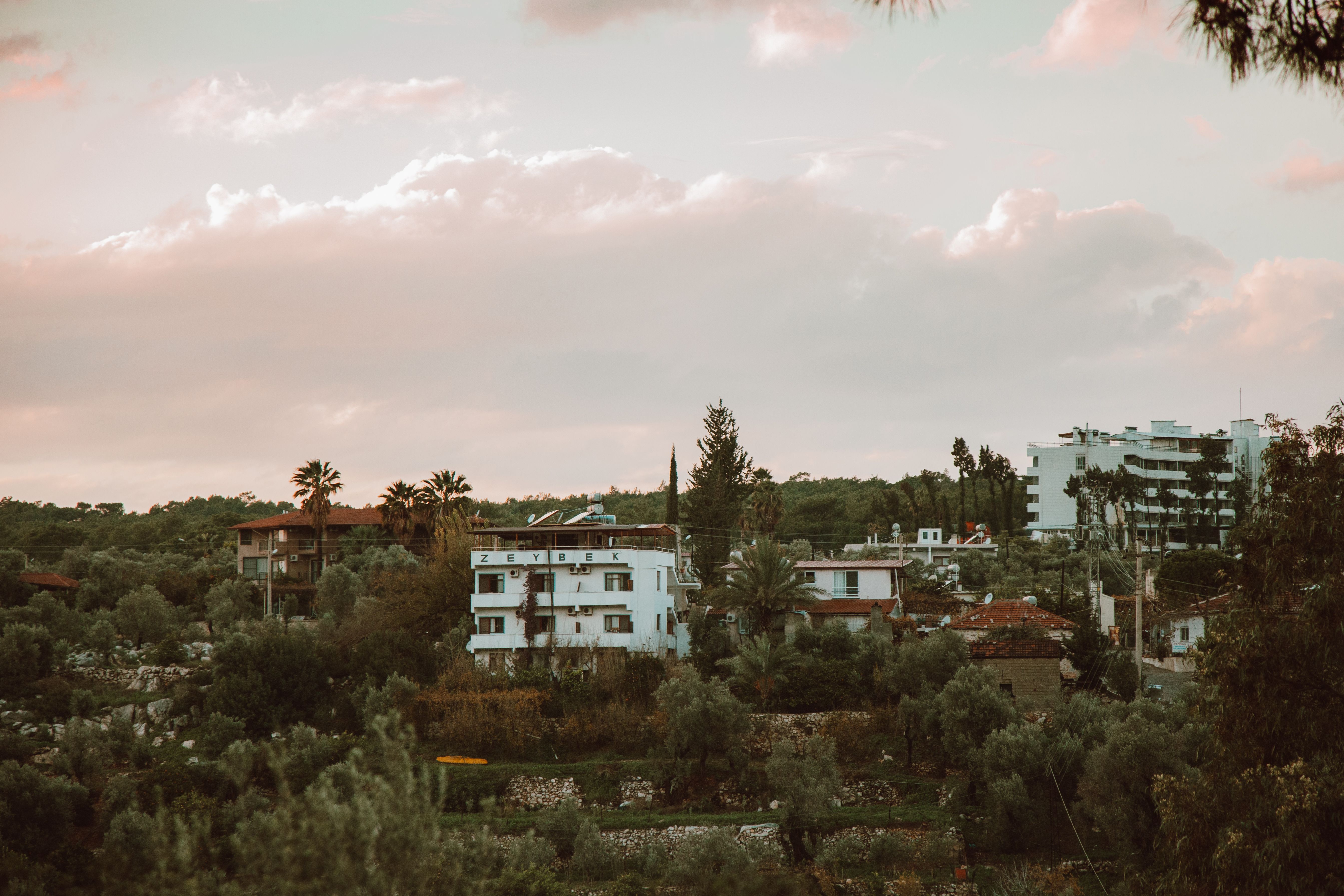 Beautiful Mediterranean hillside with traditional buildings and lush greenery under cloudy skies.