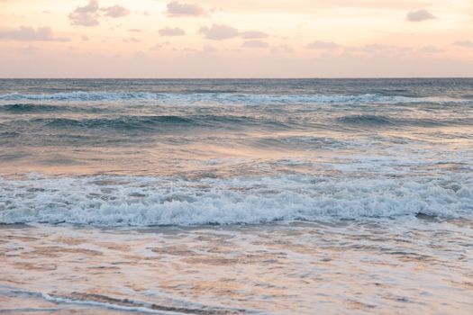 Serene ocean scene with gentle waves under a picturesque sunset sky.