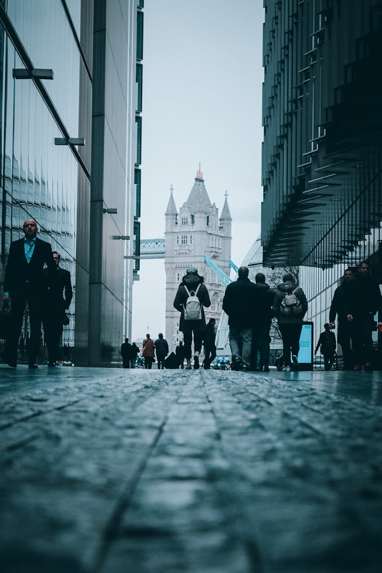 A Low Angle Shot Of People Walking On The Street Between Buildings