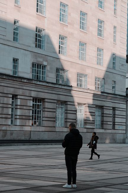 Street scene in London capturing people against a building facade with striking shadows.