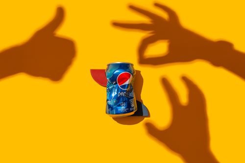 Free Vibrant flat lay image of a soda can with playful hand shadows on a bright background. Stock Photo