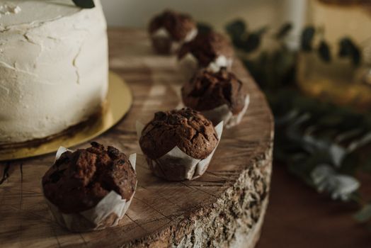 A rustic display of chocolate muffins and a cake on a wooden slab, perfect for food photography.