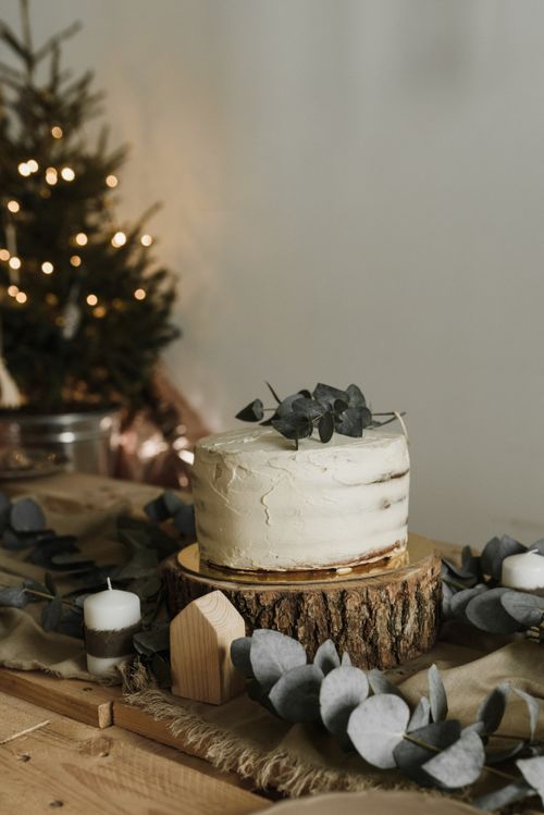 Free A beautifully decorated rustic cake with holiday decor and Christmas tree in the background. Stock Photo
