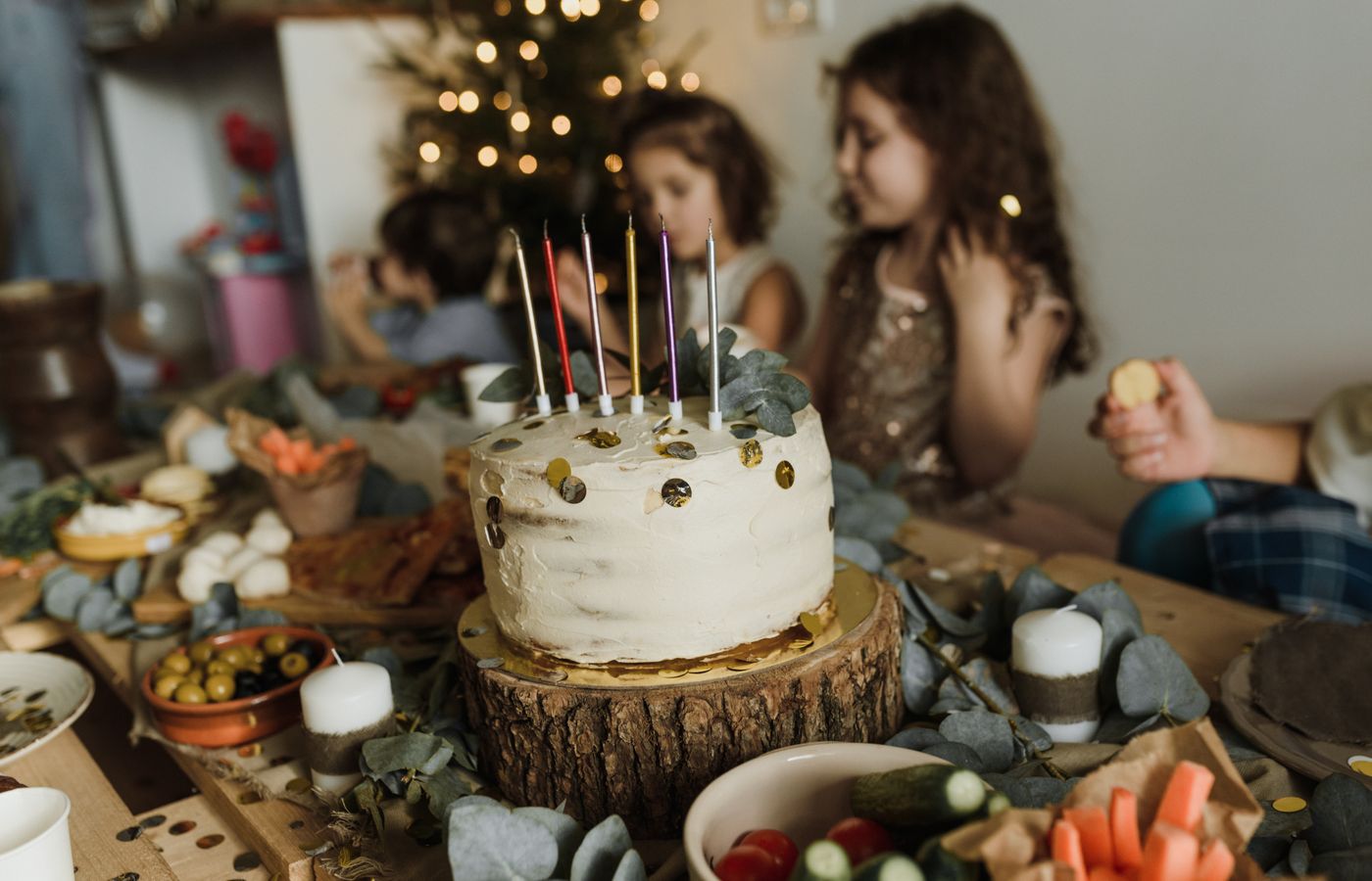 A festive birthday scene with children, cake, and decorations indoors.