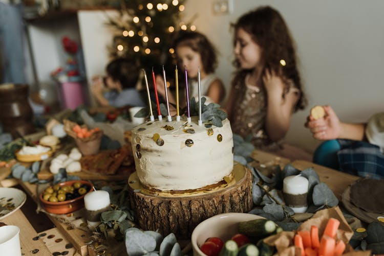 A White Cake With Candles On A Wooden Dining Table