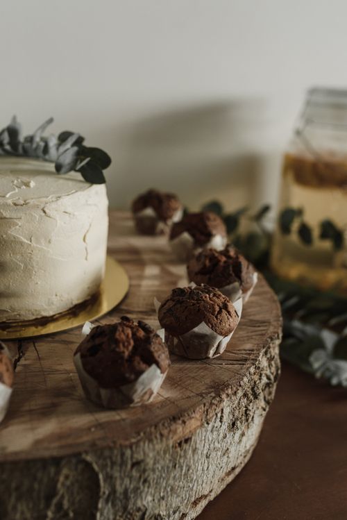 Free A rustic wooden cake stand holding chocolate cupcakes and a frosted cake, perfect for cozy dessert settings. Stock Photo