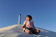 Little Girl Sitting in Snow under Blue Sky