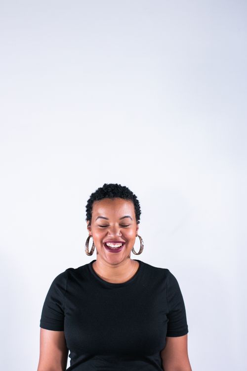 Free Portrait of a smiling woman with short curly hair and earrings against a white background. Stock Photo