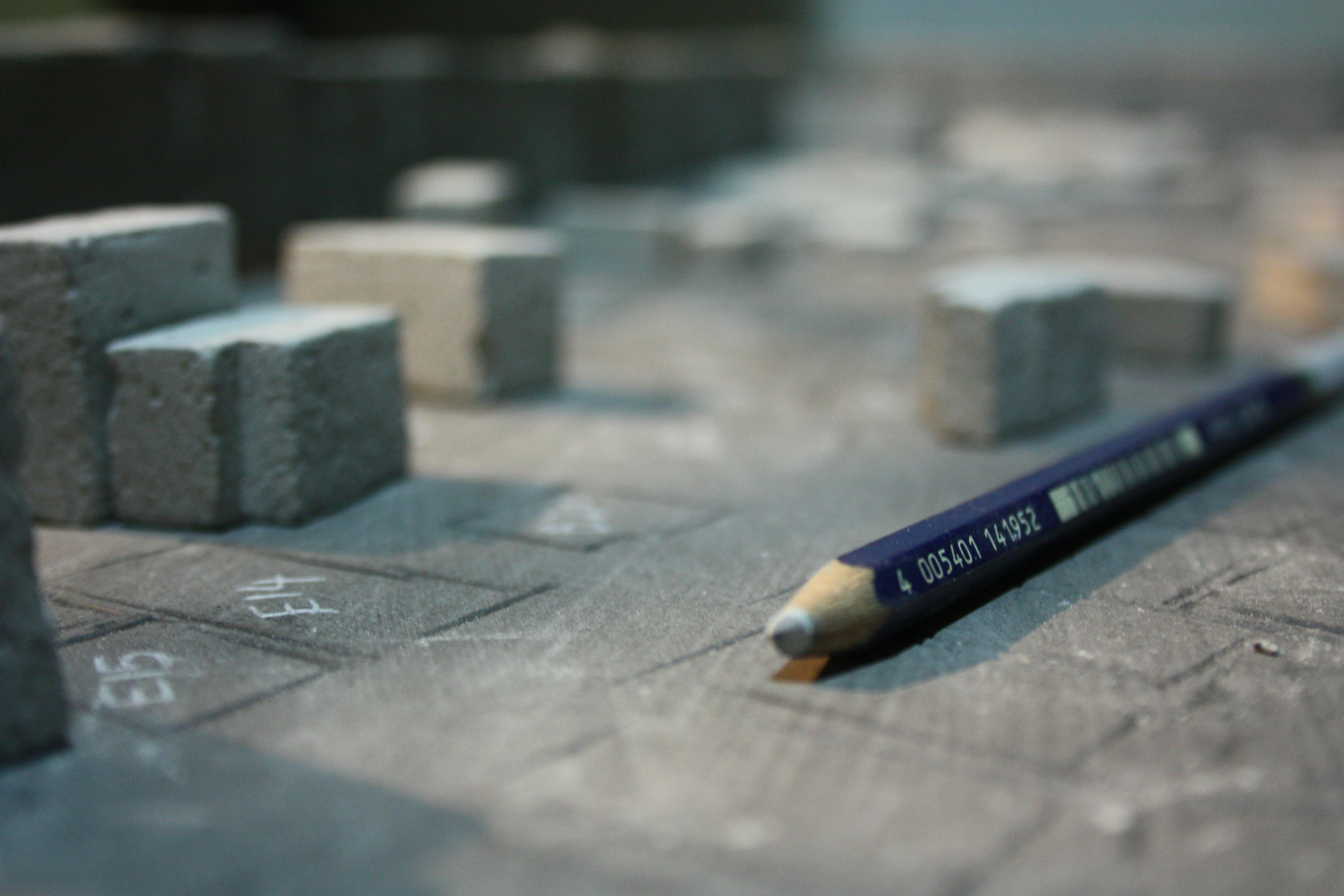 A detailed close-up of a pencil alongside architectural model blocks.