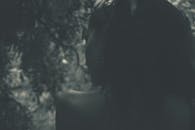 一张从背后拍摄的单色户外女性肖像，黑色调，情绪阴郁