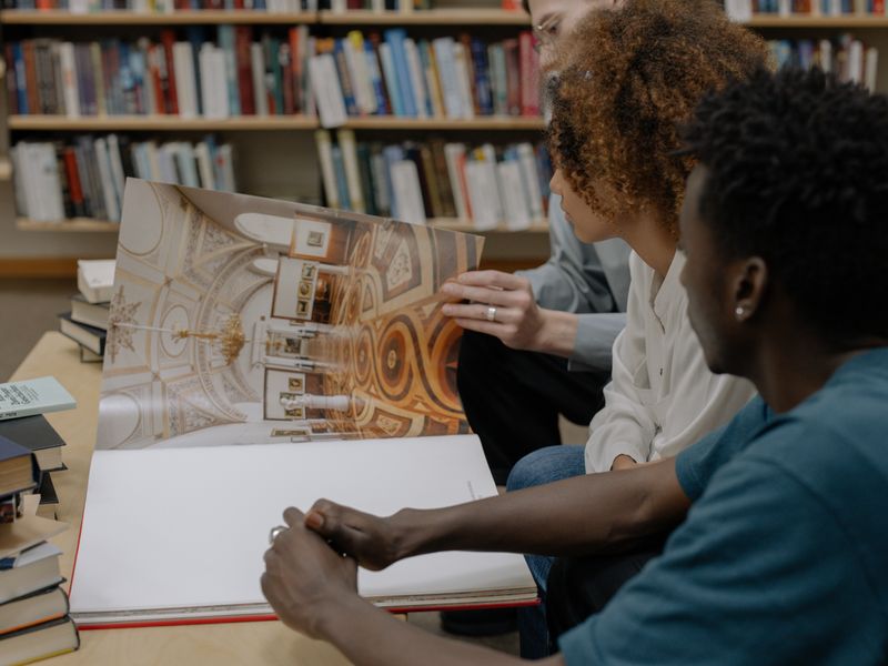 Diverse group of adults studying a large book together in a library setting - genealogy society outings