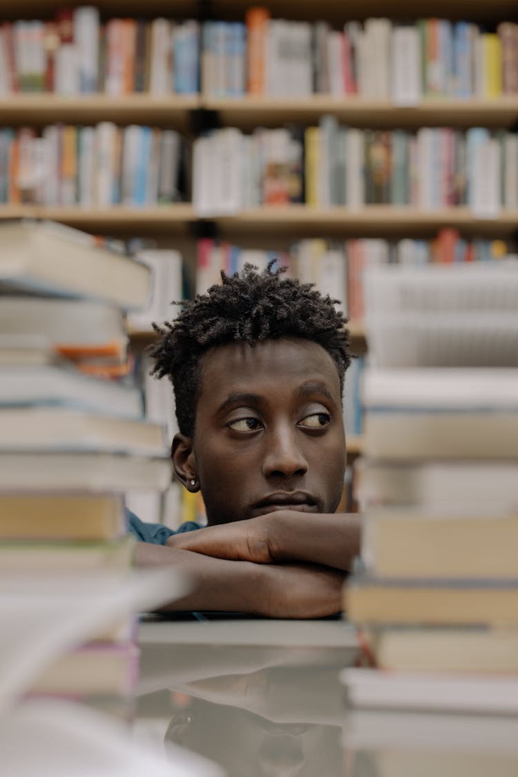 A Man Sitting Behind Stack Of Books