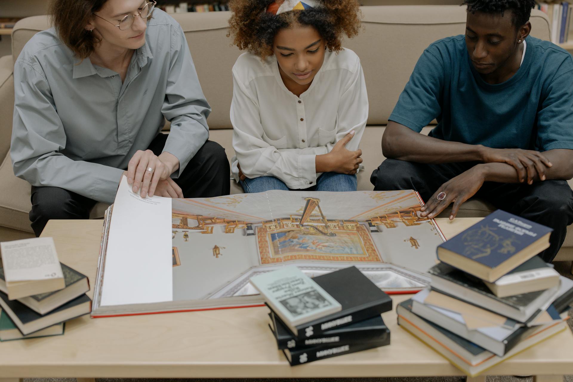 A diverse group of young adults studying together with books open on a table.