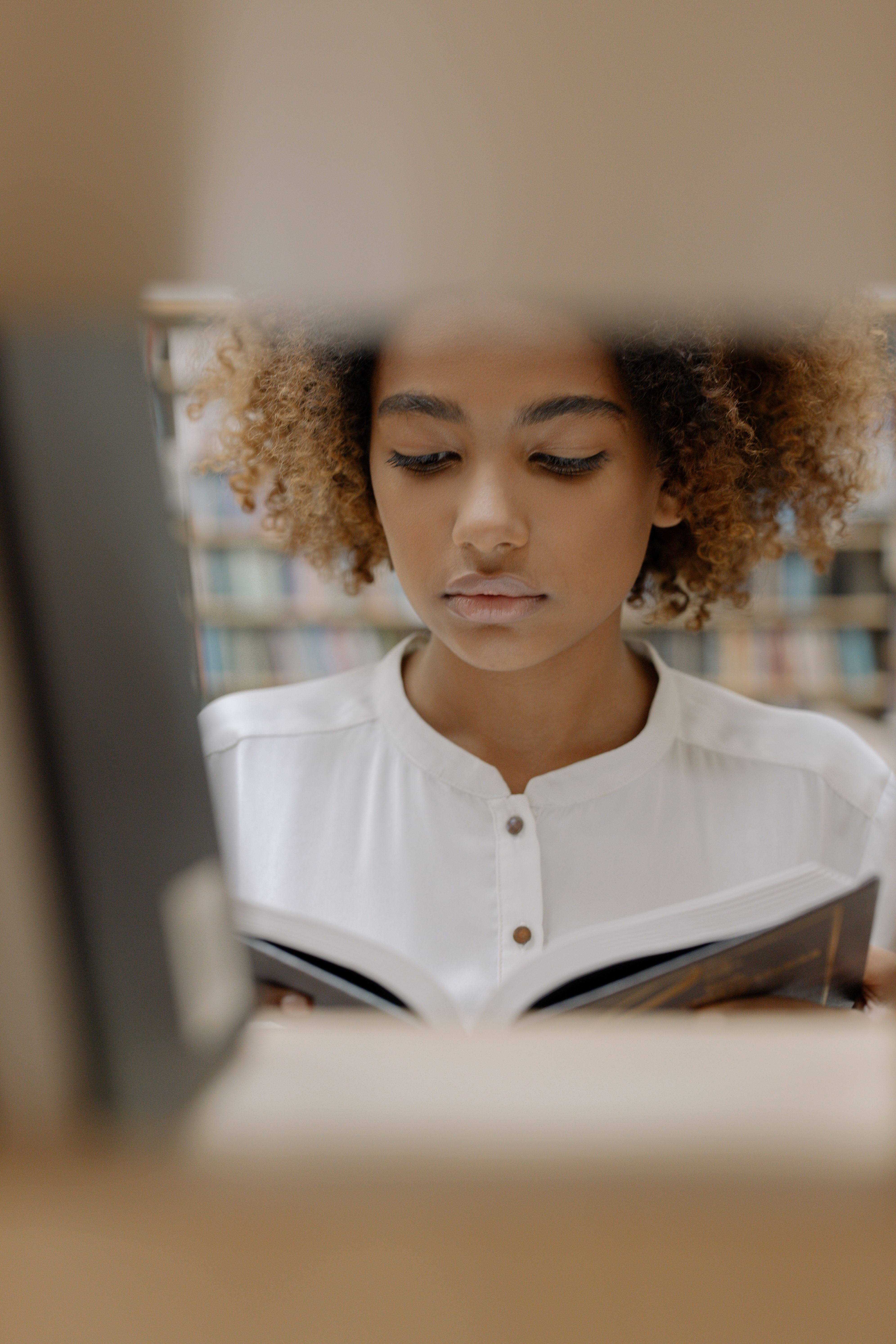 Portrait of a woman deeply engaged in reading a book at a library, surrounded by shelves of knowledge.