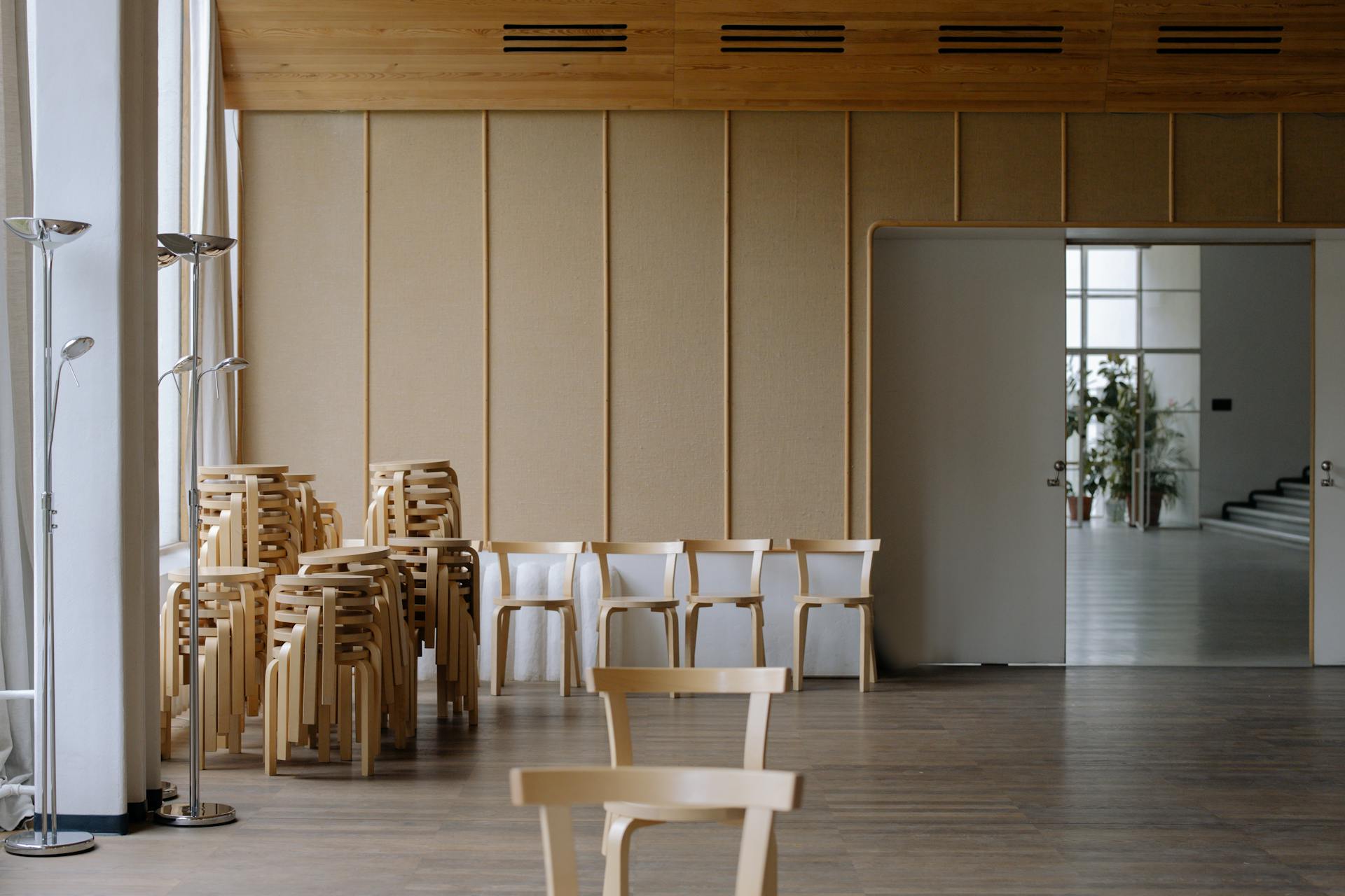 A minimalist room with stackable wooden chairs and a neutral color palette, perfect for modern designs.
