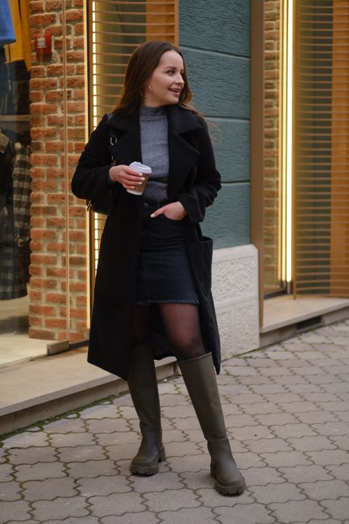 Free Full body of confident young lady in stylish outfit with takeaway cup of drink looking away while standing on city street near building with windows in daytime Stock Photo